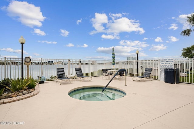 view of swimming pool with a hot tub, a water view, and a patio area