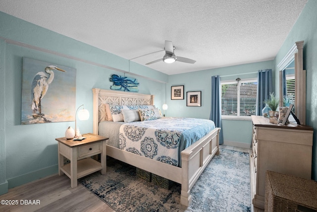 bedroom with ceiling fan, light hardwood / wood-style flooring, and a textured ceiling