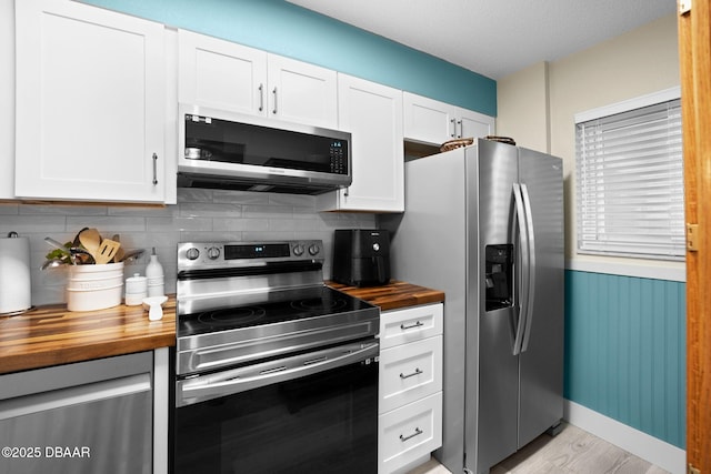 kitchen featuring wooden counters, white cabinetry, stainless steel appliances, light hardwood / wood-style floors, and decorative backsplash