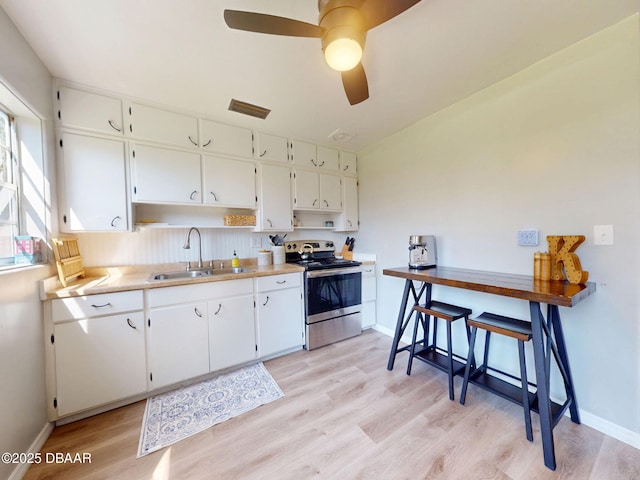 903 Conrad Dr, New Smyrna Beach, FL 32168 - kitchen with electric stove, light wood-type flooring, white cabinetry, and a ceiling fan