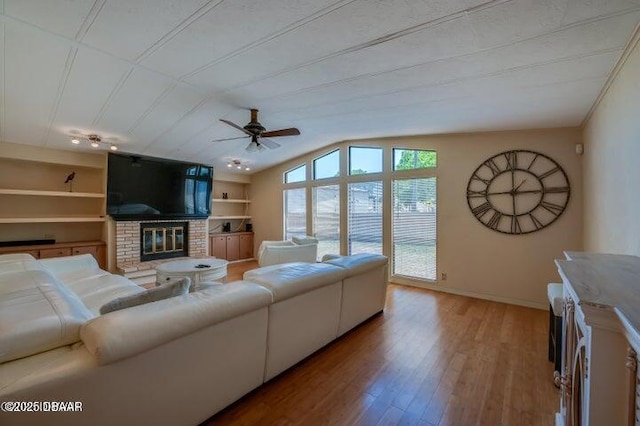 1018 Green Acres Cir Unit N, South Daytona, FL 32119 - living area featuring a brick fireplace, wood finished floors, ceiling fan, built in shelves, and vaulted ceiling