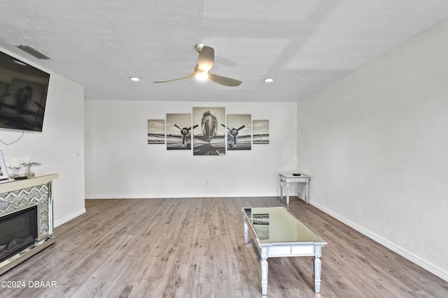 interior space with light hardwood / wood-style floors, ceiling fan, and a tiled fireplace