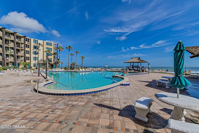 view of pool featuring a patio, a water view, and a gazebo