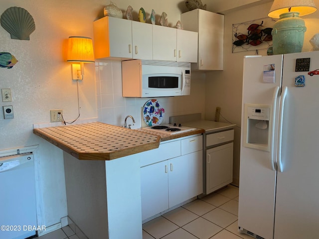 kitchen featuring white cabinets, decorative backsplash, kitchen peninsula, light tile patterned floors, and white appliances