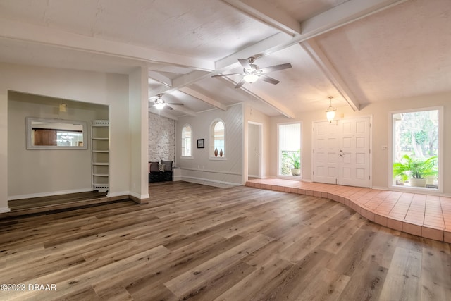 unfurnished living room featuring hardwood / wood-style floors, a wealth of natural light, and lofted ceiling with beams