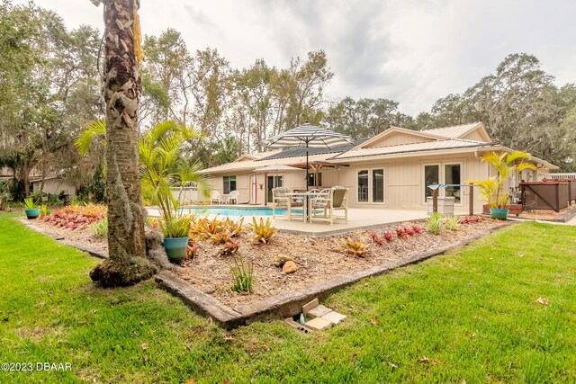 rear view of house featuring a patio, a yard, and a swimming pool with hot tub