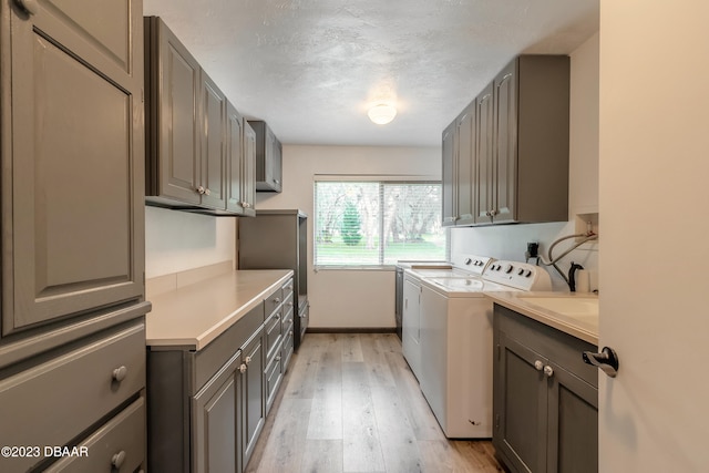 laundry area with cabinets, light hardwood / wood-style floors, separate washer and dryer, and a textured ceiling