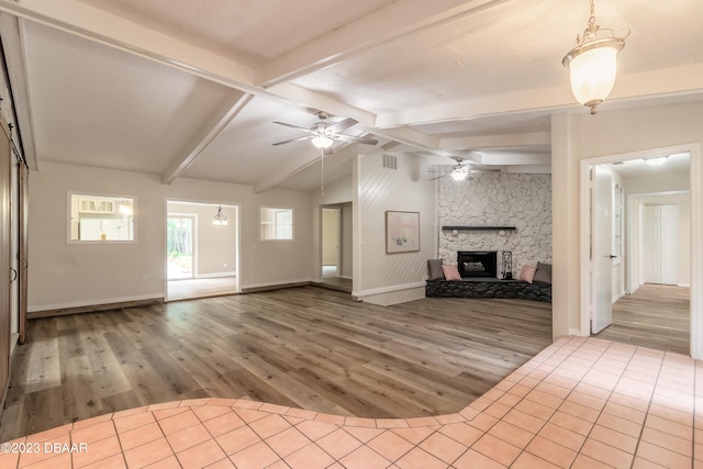 unfurnished living room featuring hardwood / wood-style floors, a fireplace, lofted ceiling with beams, and ceiling fan