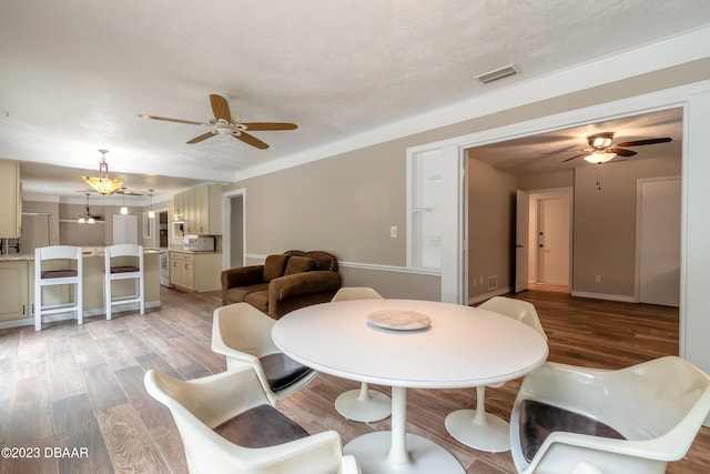 dining space with light wood-type flooring and ceiling fan with notable chandelier