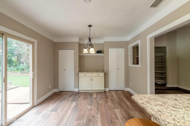 unfurnished dining area featuring a chandelier, wood-type flooring, and ornamental molding