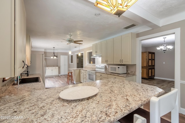 kitchen featuring white appliances, dark hardwood / wood-style floors, a breakfast bar area, kitchen peninsula, and ceiling fan with notable chandelier