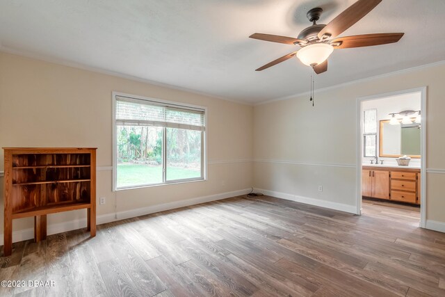 empty room with ceiling fan, sink, crown molding, and light hardwood / wood-style flooring