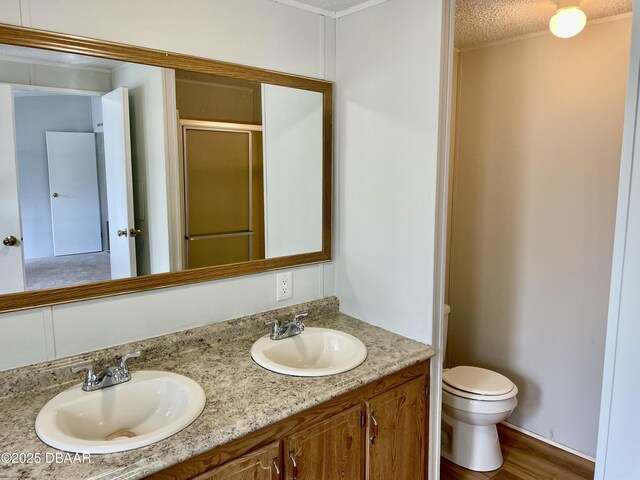 1910 Woodcrest Dr, Ormond Beach, FL 32174 - full bathroom with double vanity, toilet, a shower with door, wood finished floors, and a textured ceiling