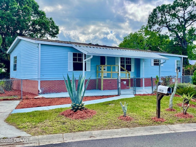 1910 Woodcrest Dr, Ormond Beach, FL 32174 - manufactured / mobile home with covered porch, metal roof, and a gate