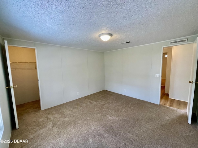 1910 Woodcrest Dr, Ormond Beach, FL 32174 - unfurnished bedroom featuring carpet floors, a walk in closet, a textured ceiling, and a closet