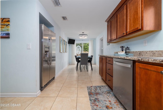 127 Bosarvey Dr, Ormond Beach, FL 32176 - kitchen with stainless steel appliances, brown cabinets, light tile patterned floors, and a chandelier