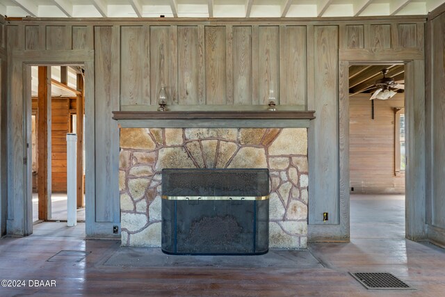 interior details with a stone fireplace, wood walls, hardwood / wood-style flooring, beamed ceiling, and ceiling fan