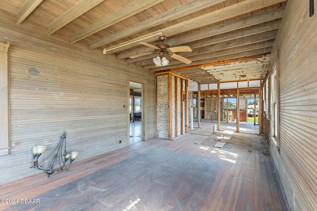 interior space with wood walls, ceiling fan, beam ceiling, and wood-type flooring