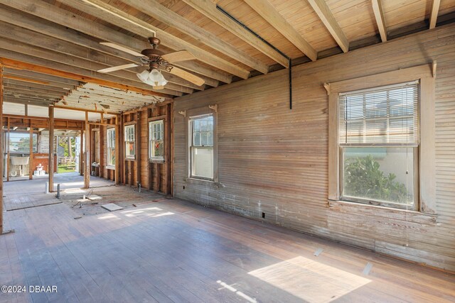 interior space with beamed ceiling, ceiling fan, wooden walls, and wood-type flooring