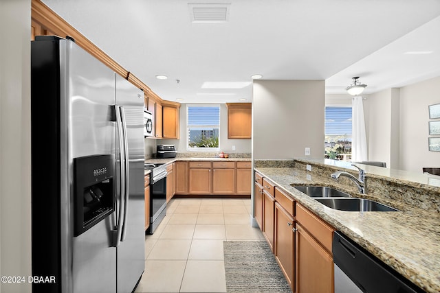 kitchen featuring light stone countertops, a wealth of natural light, sink, and stainless steel appliances