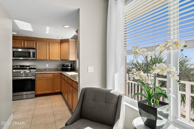 kitchen with light stone counters, light tile patterned floors, and stainless steel appliances