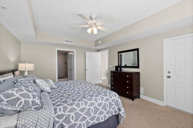 bedroom featuring a closet, a walk in closet, light carpet, and ceiling fan