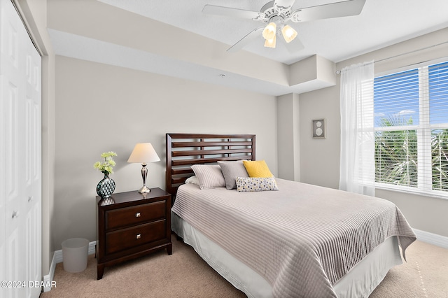 bedroom featuring light carpet, ceiling fan, and a closet