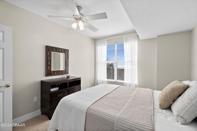 carpeted bedroom with ceiling fan and a textured ceiling