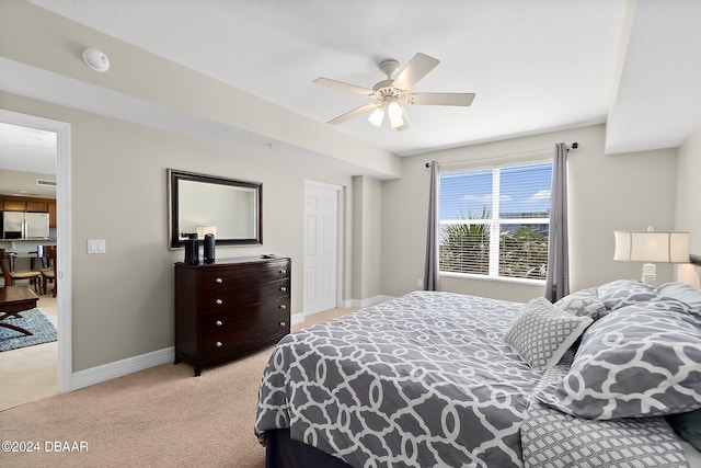 bedroom with light colored carpet, ceiling fan, and stainless steel fridge