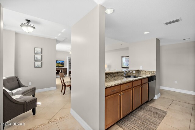 kitchen with dishwasher, light stone countertops, sink, and light tile patterned flooring