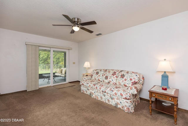 living area with ceiling fan, carpet floors, and a textured ceiling