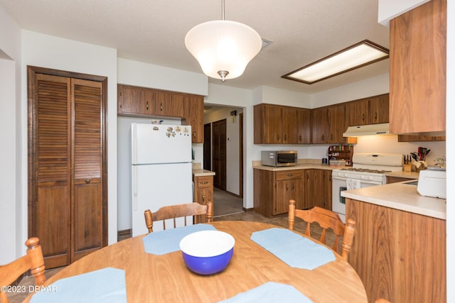 kitchen featuring a textured ceiling, white appliances, and hanging light fixtures