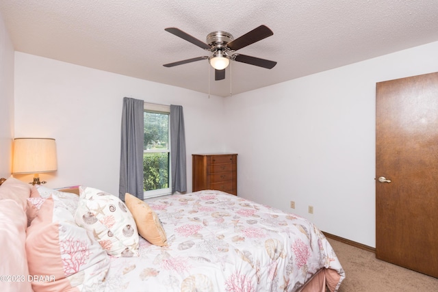 bedroom with ceiling fan, light colored carpet, and a textured ceiling