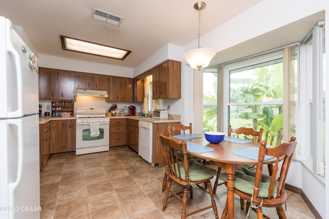 kitchen with a textured ceiling, sink, white appliances, and hanging light fixtures