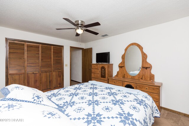 carpeted bedroom featuring a textured ceiling, a closet, and ceiling fan