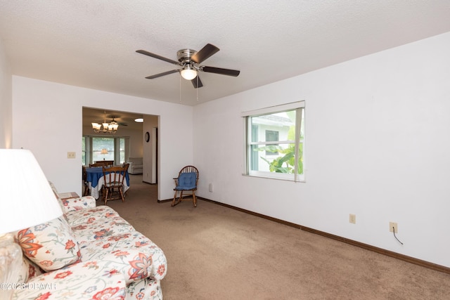 interior space with a textured ceiling, carpet floors, and ceiling fan with notable chandelier