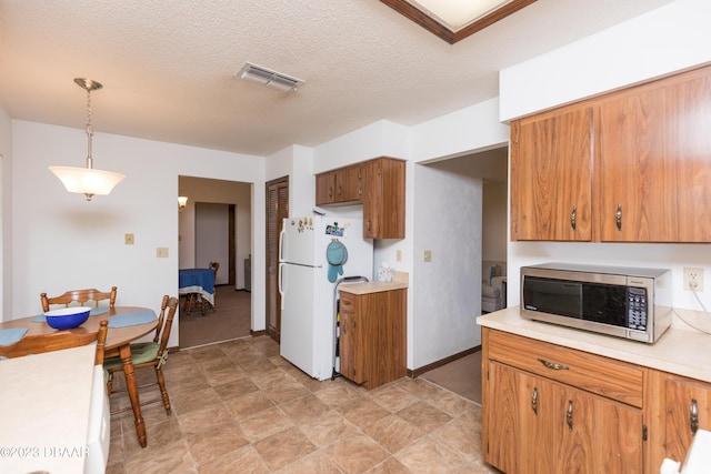 kitchen featuring a textured ceiling, decorative light fixtures, and white refrigerator