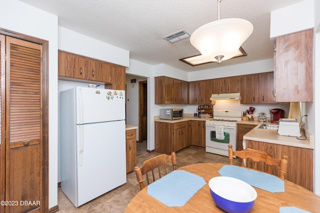 kitchen with decorative light fixtures, white appliances, and a textured ceiling