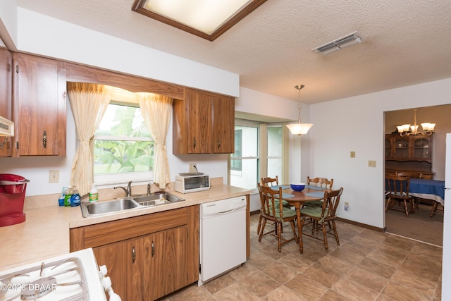 kitchen featuring pendant lighting, a textured ceiling, white dishwasher, and sink