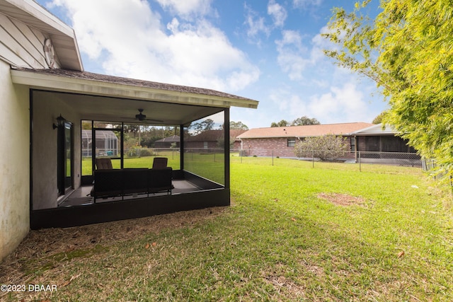 view of yard featuring a sunroom and ceiling fan