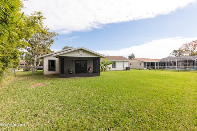 rear view of property with a sunroom, central AC unit, and a lawn