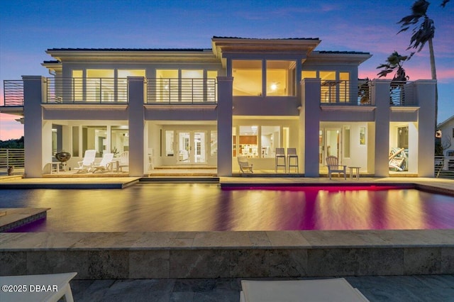 back of house with a balcony, a patio area, an outdoor pool, and stucco siding