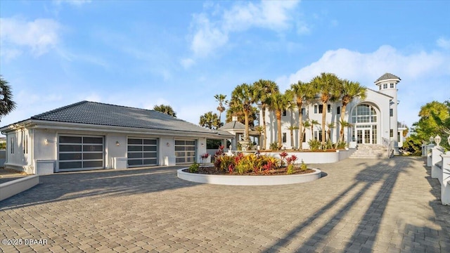 view of front of home with a tiled roof, decorative driveway, an attached garage, and stucco siding