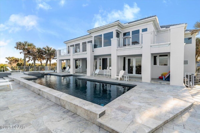 rear view of house featuring a patio area, stucco siding, french doors, and a balcony