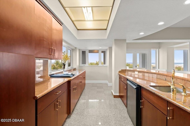 kitchen featuring baseboards, dishwasher, light stone counters, granite finish floor, and a sink