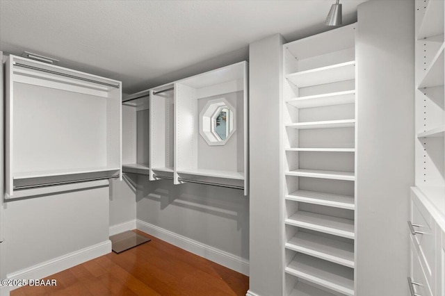 walk in closet with dark wood-style floors