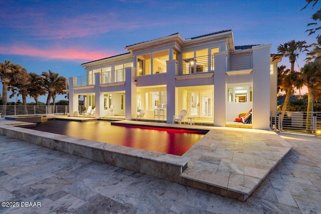 rear view of house with stucco siding, fence, a balcony, and a patio area