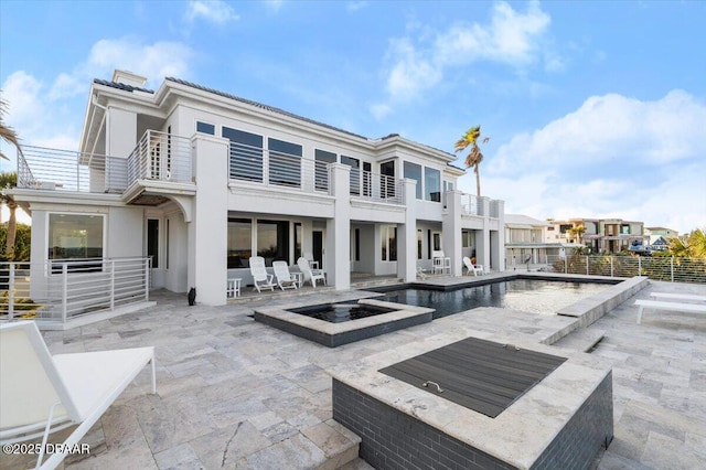 rear view of house with stucco siding, an outdoor fire pit, a fenced in pool, a balcony, and a patio area