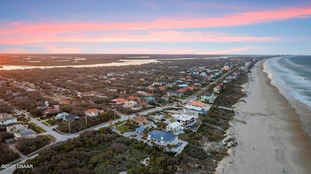 aerial view at dusk featuring a beach view and a water view