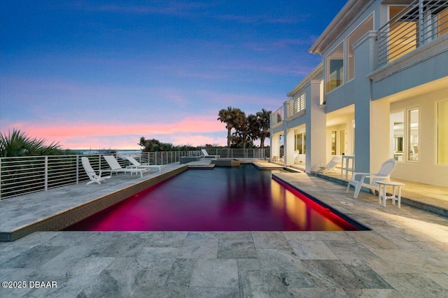 pool at dusk featuring a patio area, a fenced in pool, and fence